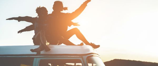 Two people sitting on a Van in the sunset