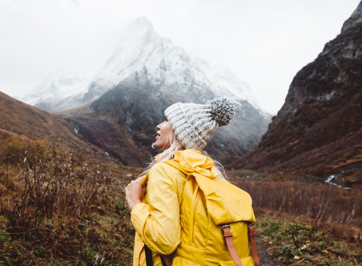 Woman in yellow raincoat with mountain 